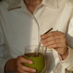 일상 속 건강을 챙기는 ‘웰니스 문화’…작은 변화로 큰 행복 찾기 person in white button up shirt holding clear drinking glass with green liquid